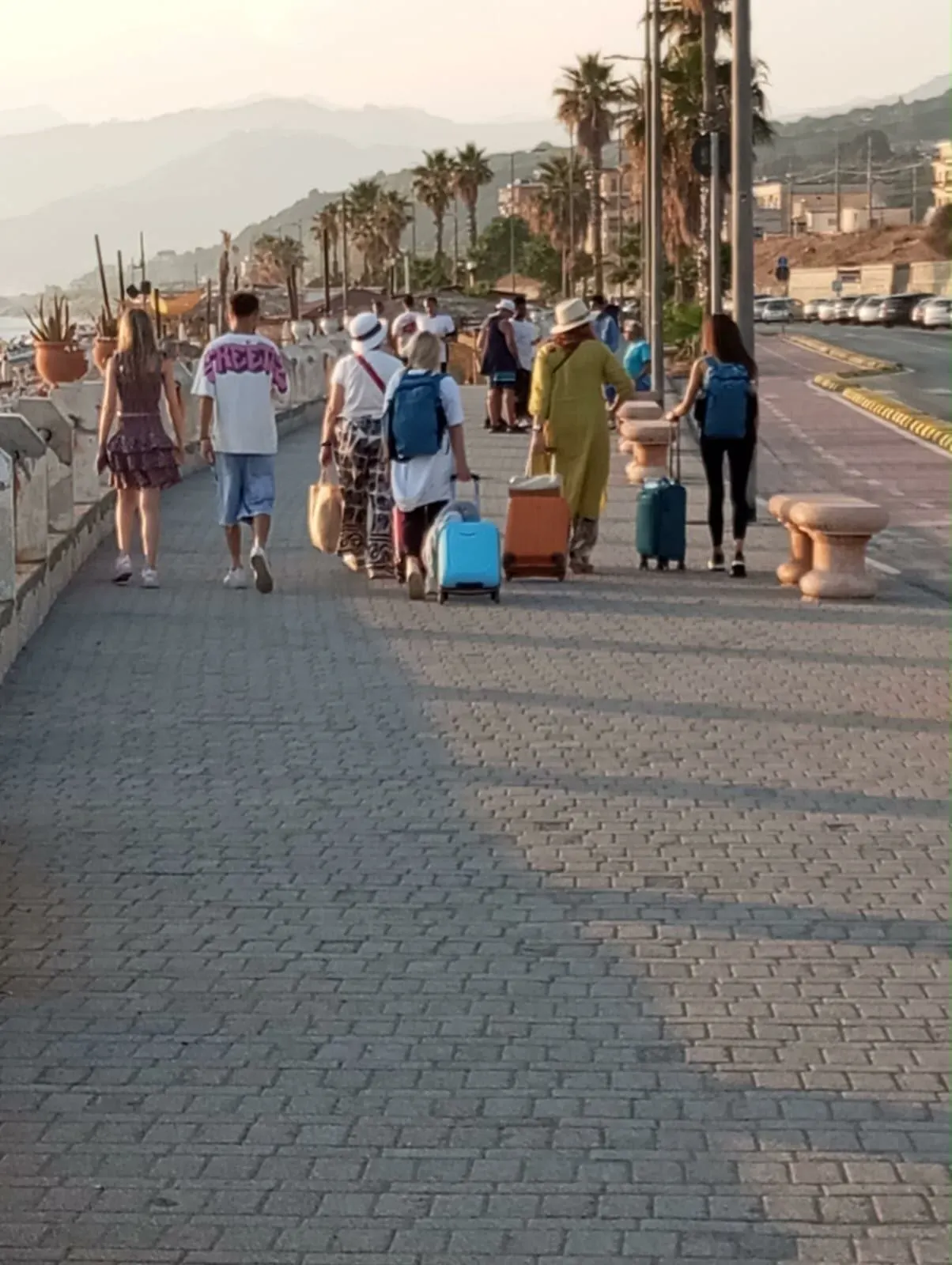 Viaggiatori con le valigie sul lungomare di Paola
