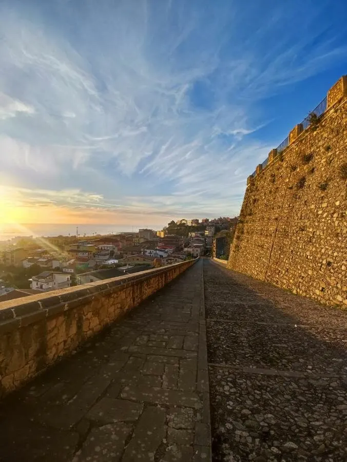 Le mura antiche di Paola con la costa e le colline al tramonto